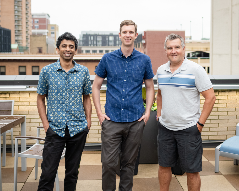 OfferingTree co-founders Chris Appiah, Alex Haley, and Tom McCook standing together outdoors on a rooftop.
