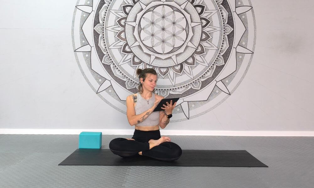 Yoga teacher using OfferingTree scheduling and studio management tools on a tablet at a yoga studio.