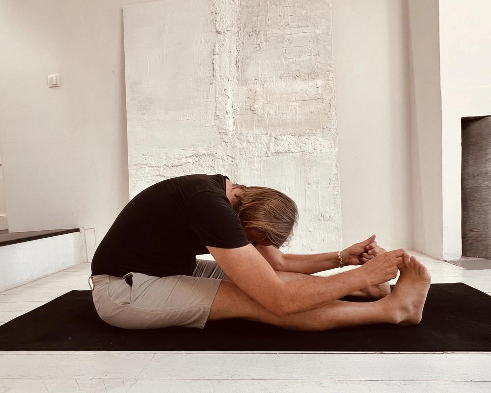 Jesse Gabler practicing a deep seated forward fold (Paschimottanasana) while illustrating one of the yoga poses that may aggravate lower back pain for some people with lumbar disc issues. This personal example accompanies his article on yoga for back pain, explaining how excessive spinal flexion can increase stress on the lumbar spine and why maintaining length through the spine and hinging from the hips may be a safer approach.