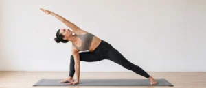 Woman practicing Extended Side Angle Pose with one hand beside the front foot and the opposite arm reaching overhead.